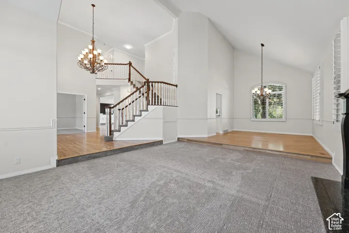 Vaulted ceilings with decorative chandeliers, a split-level design, and a grand staircase with wood railing