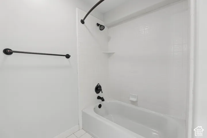 White subway tile shower surround with integrated shelving and a white bathtub