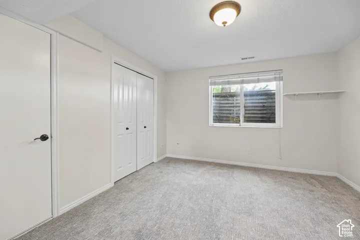 Recessed lighting with a bronze-finish fixture, white bi-fold closet doors, and light gray carpet flooring