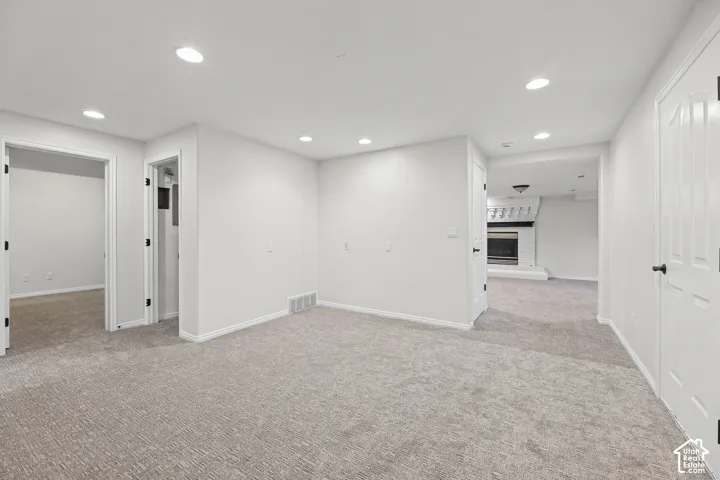 Neutral carpet flooring in a spacious room featuring recessed lighting