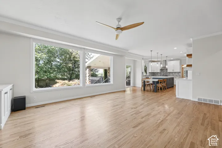 Expansive wood-finish flooring with a modern ceiling fan and large picture windows