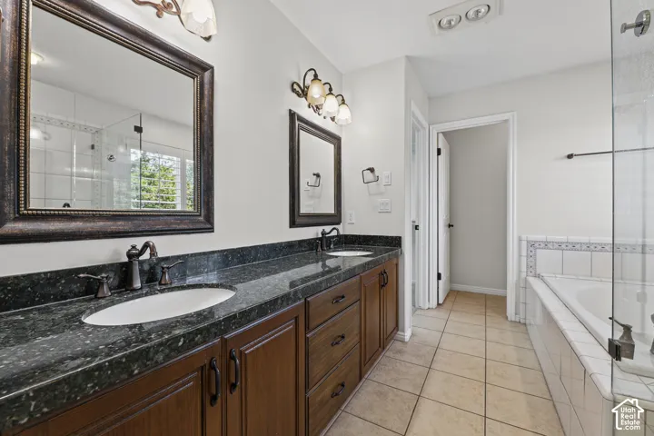 Double vanity with dark stone-finish countertop, wood-finish cabinetry, and oil-rubbed bronze fixtures