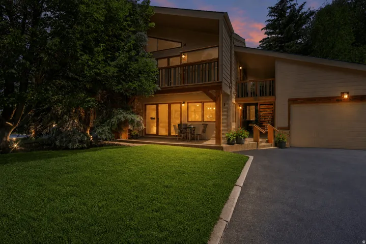 Contemporary architectural style with a two-car garage, upper-level balcony, and a ground-level patio