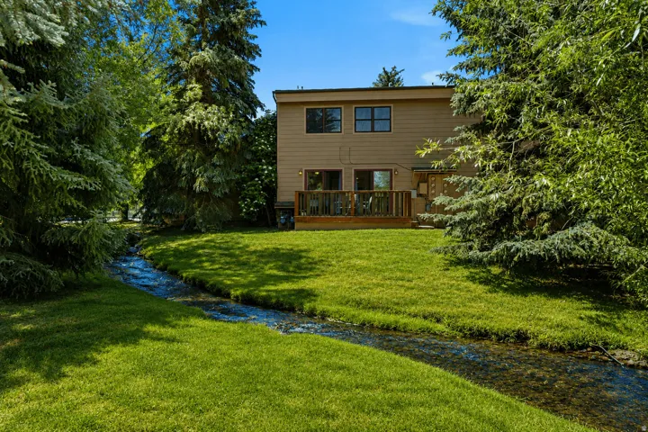 Rear exterior featuring a wood-plank deck, beige siding, and two upper-level windows