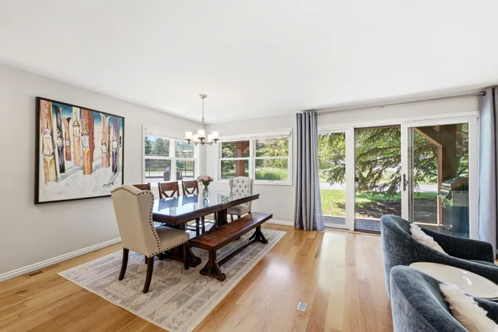 Bright dining area featuring hardwood flooring, a multi-pane window with white trim, and a glass sliding door providing access to the exterior