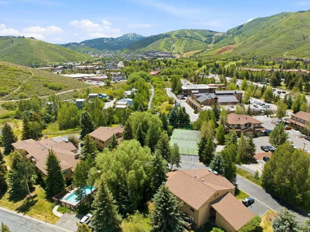 Expansive aerial perspective showcasing multiple residential buildings with brown shingle roofs, surrounded by mature evergreen and deciduous trees