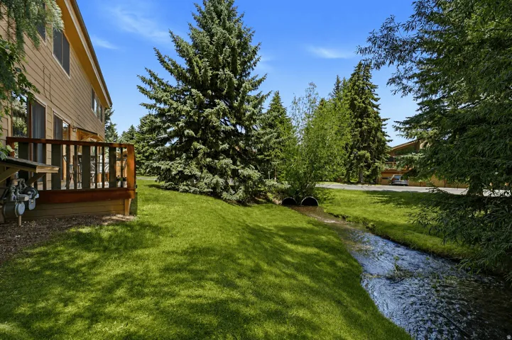 Wood deck with vertical balusters overlooking a natural stream and lush green lawn