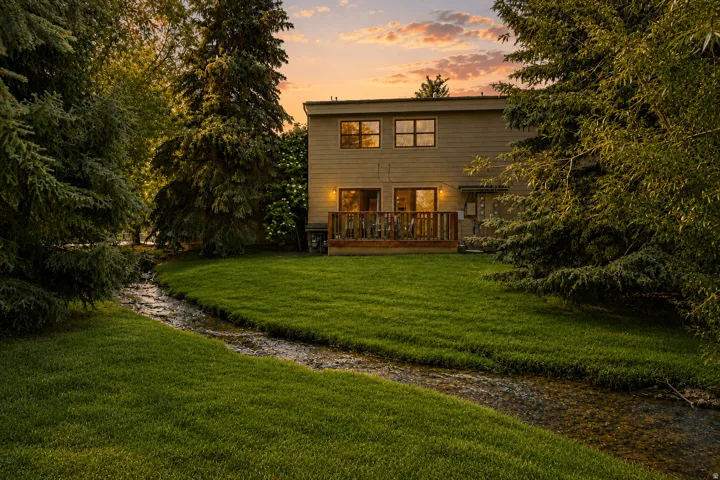 Expansive green lawn bordering a natural stream