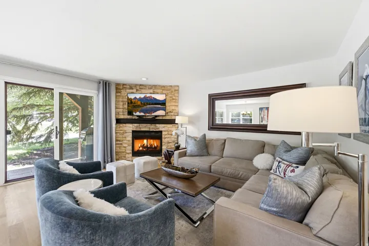 Living area featuring a stone-faced fireplace with a wood mantel, sliding glass doors, light wood-finish flooring, and recessed lighting