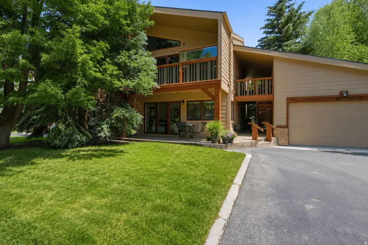 Contemporary residence featuring multiple balconies with wood railings, a two-car garage, and a lush green lawn