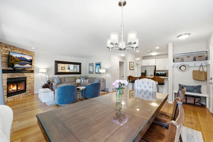 Open-concept living space featuring wood-finish flooring, a stone-clad fireplace, and recessed lighting