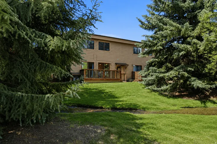 Rear exterior featuring a spacious wood deck, tan siding, and dark-framed windows