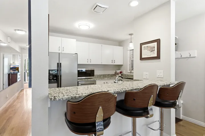 Kitchen featuring a breakfast bar with stone-finish countertop, white cabinetry, stainless steel appliances, and recessed lighting