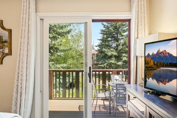 Sliding glass door opening to an outdoor deck with wood-finish railing