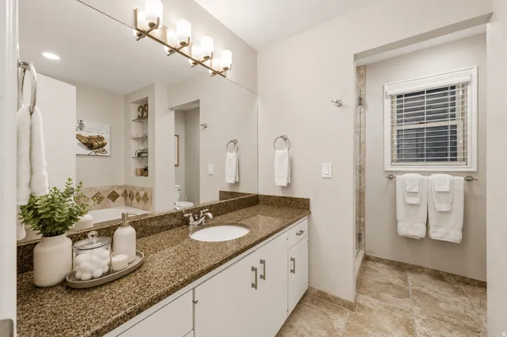 Bathroom featuring a single vanity with granite countertop, integrated sink, and white cabinetry