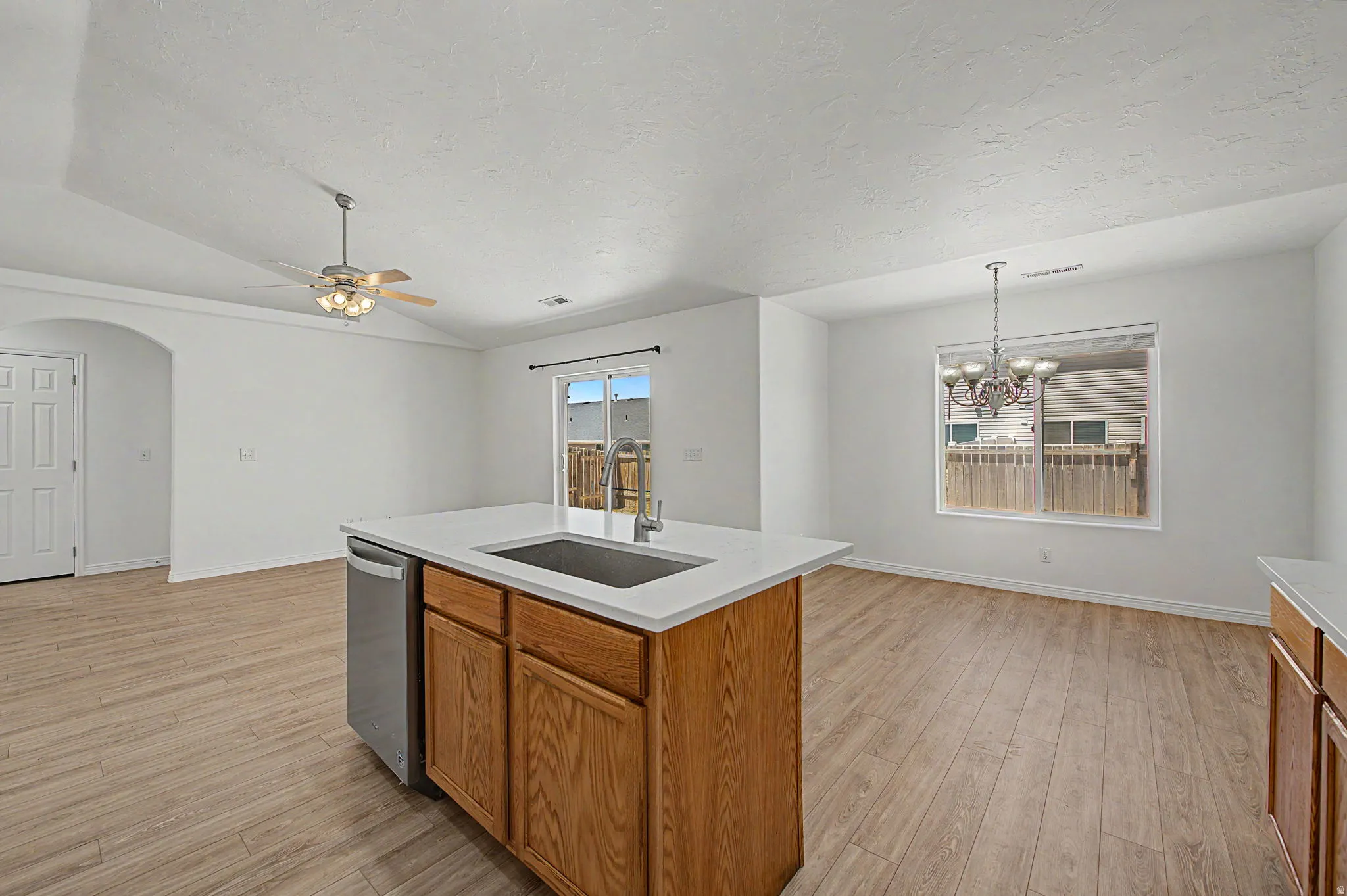 Kitchen island featuring light wood-finish cabinetry, a stainless steel sink, and a white countertop