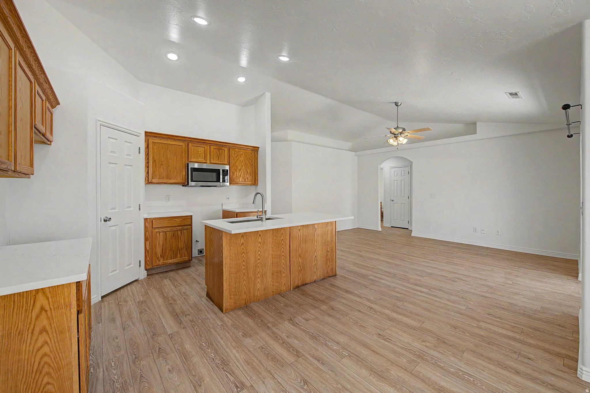 Open-concept living space featuring wood-finish flooring, vaulted ceilings, and recessed lighting