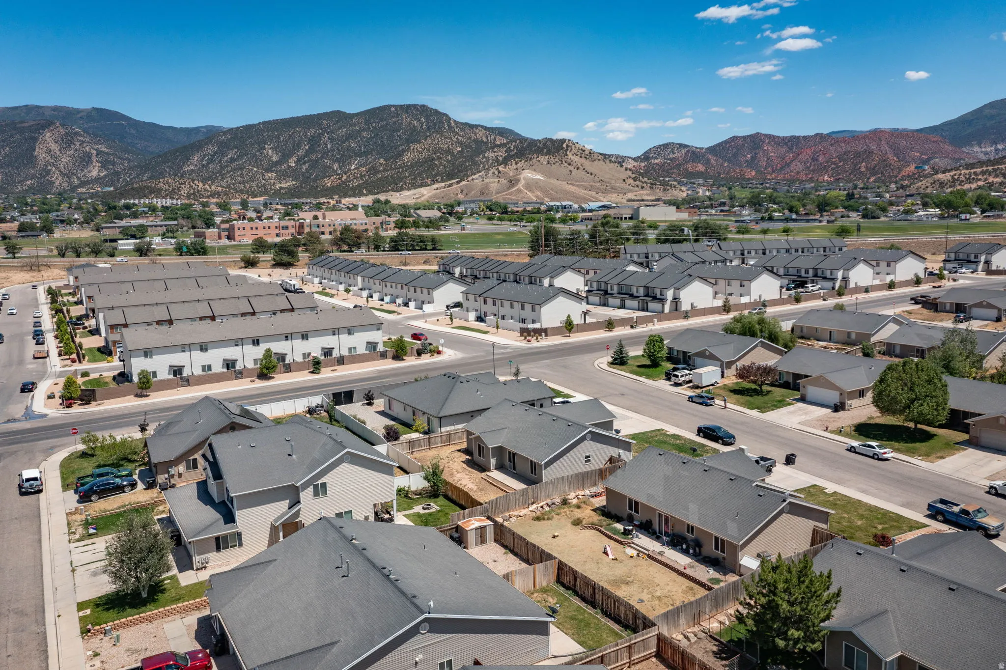 Residential neighborhood featuring a mix of single-family homes and townhomes, paved streets, and a mountainous backdrop