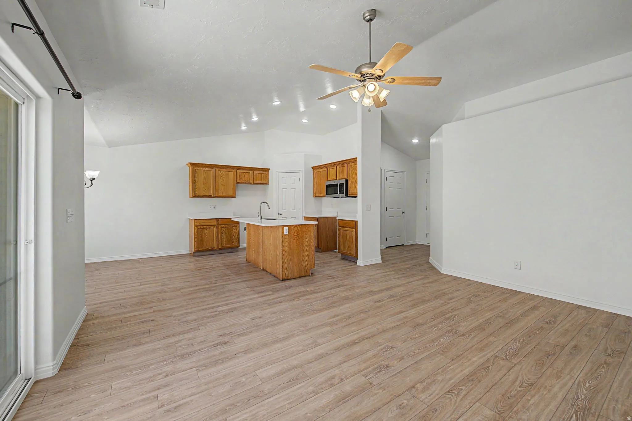 Bright kitchen featuring wood-finish cabinetry, a central island with a sink, and integrated stainless steel appliances