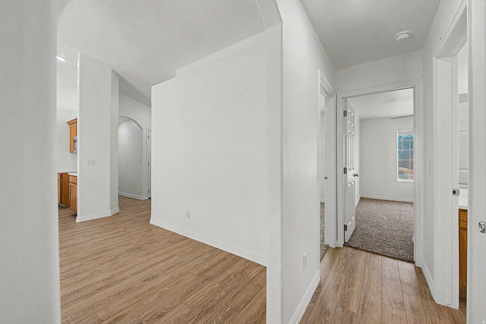 Interior hallway featuring wood-finish flooring, white walls, and white trim
