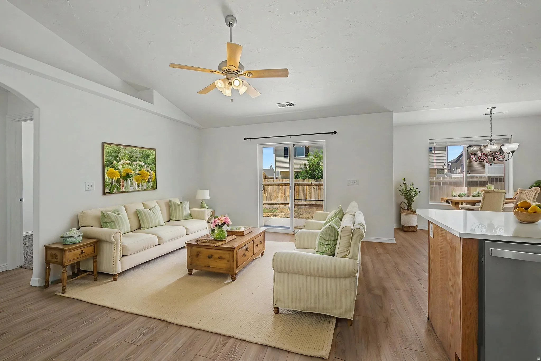 Open-concept living area featuring vaulted ceilings, wood-finish flooring, and a ceiling fan