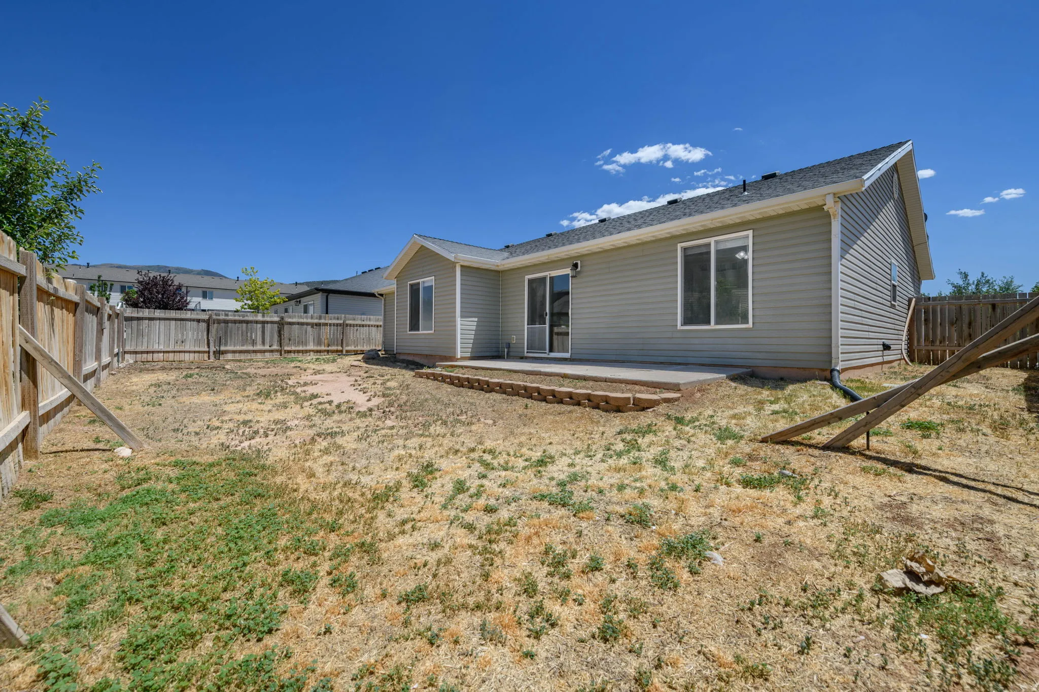 Spacious backyard featuring wood fencing and a concrete patio