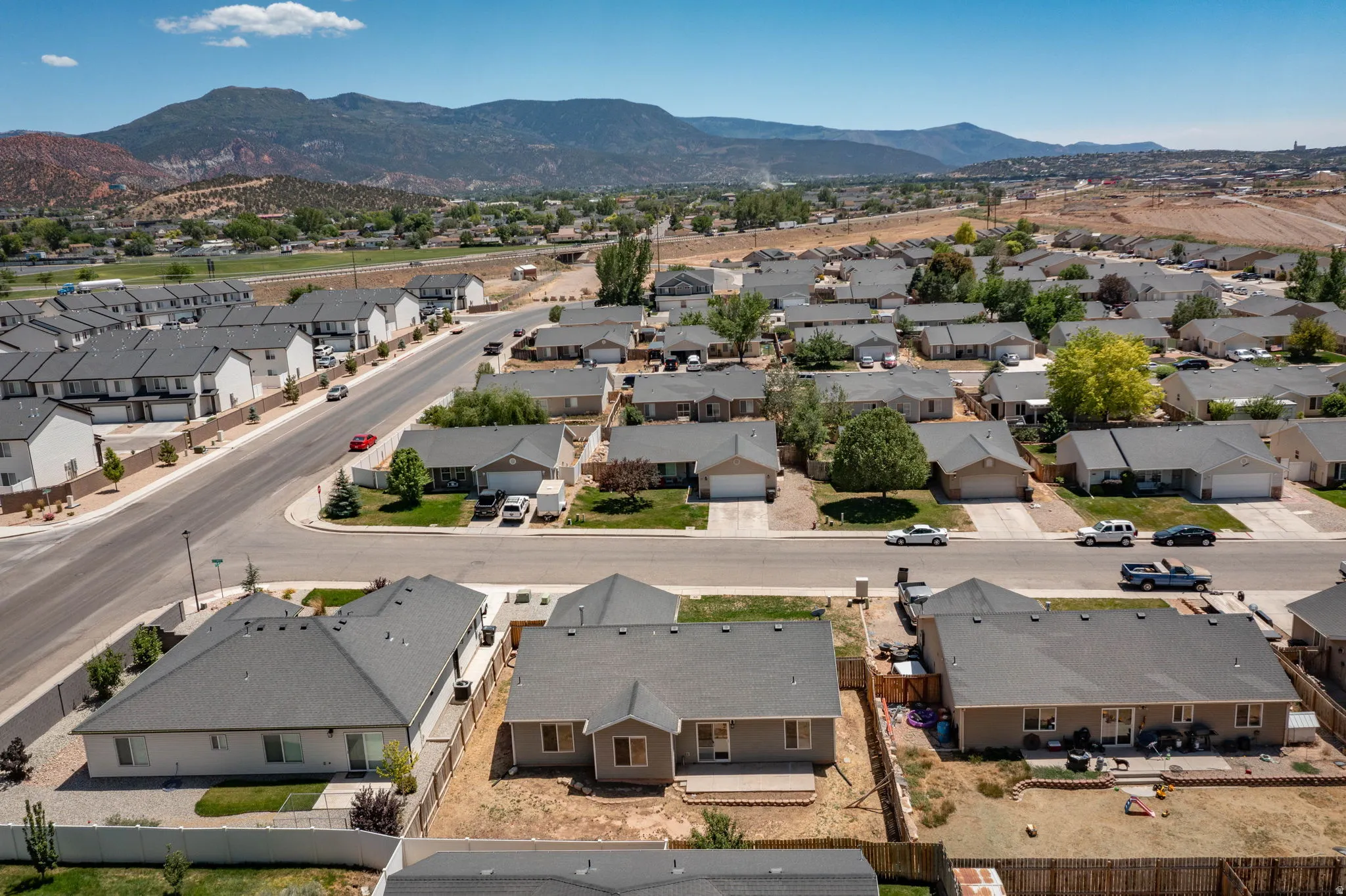 Aerial perspective of a neighborhood featuring single-story and multi-story homes with dark shingle roofing