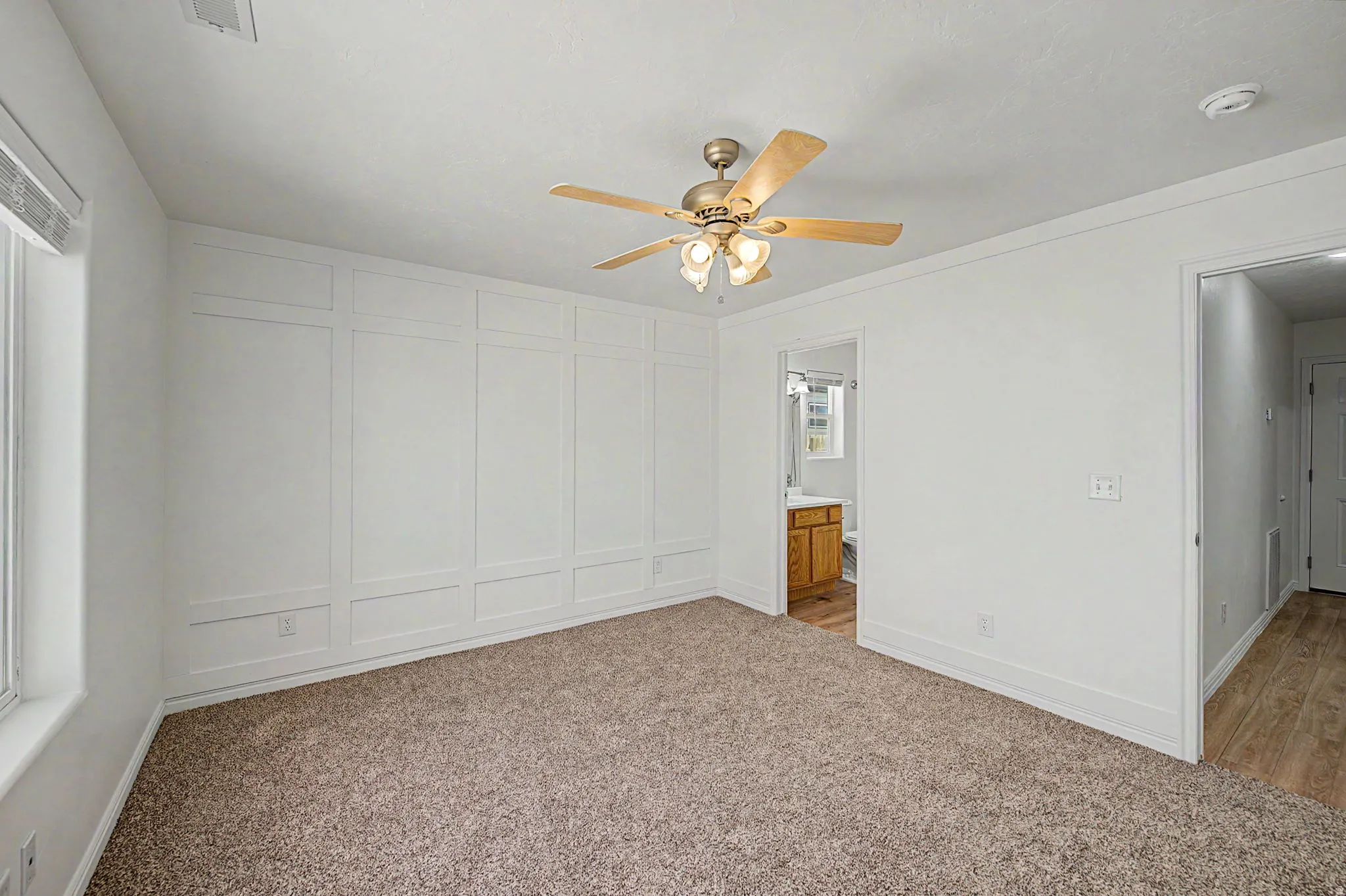 Interior room featuring a white paneled accent wall and soft brown carpeting