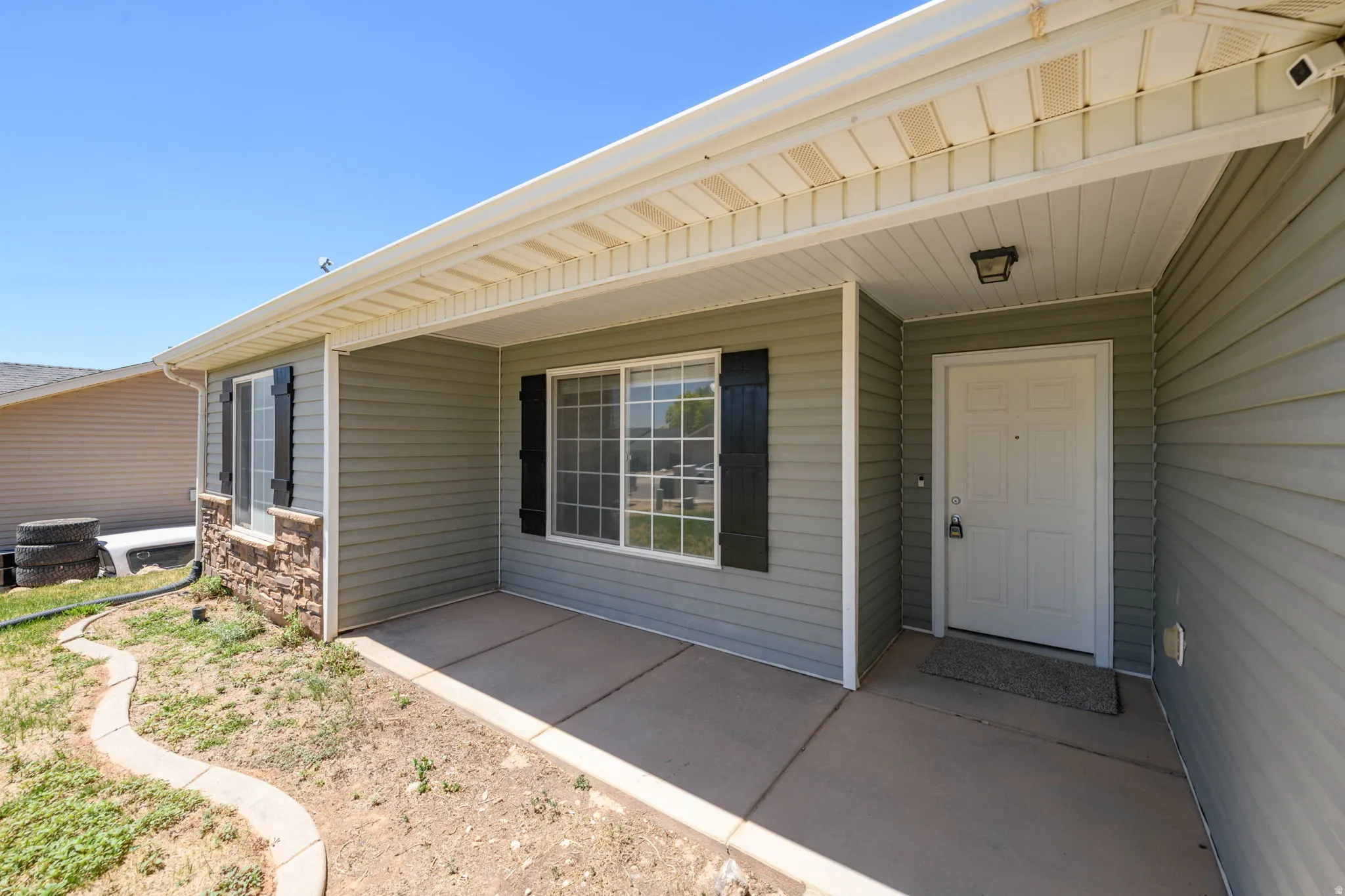 Covered entry porch featuring light green siding and decorative black shutters