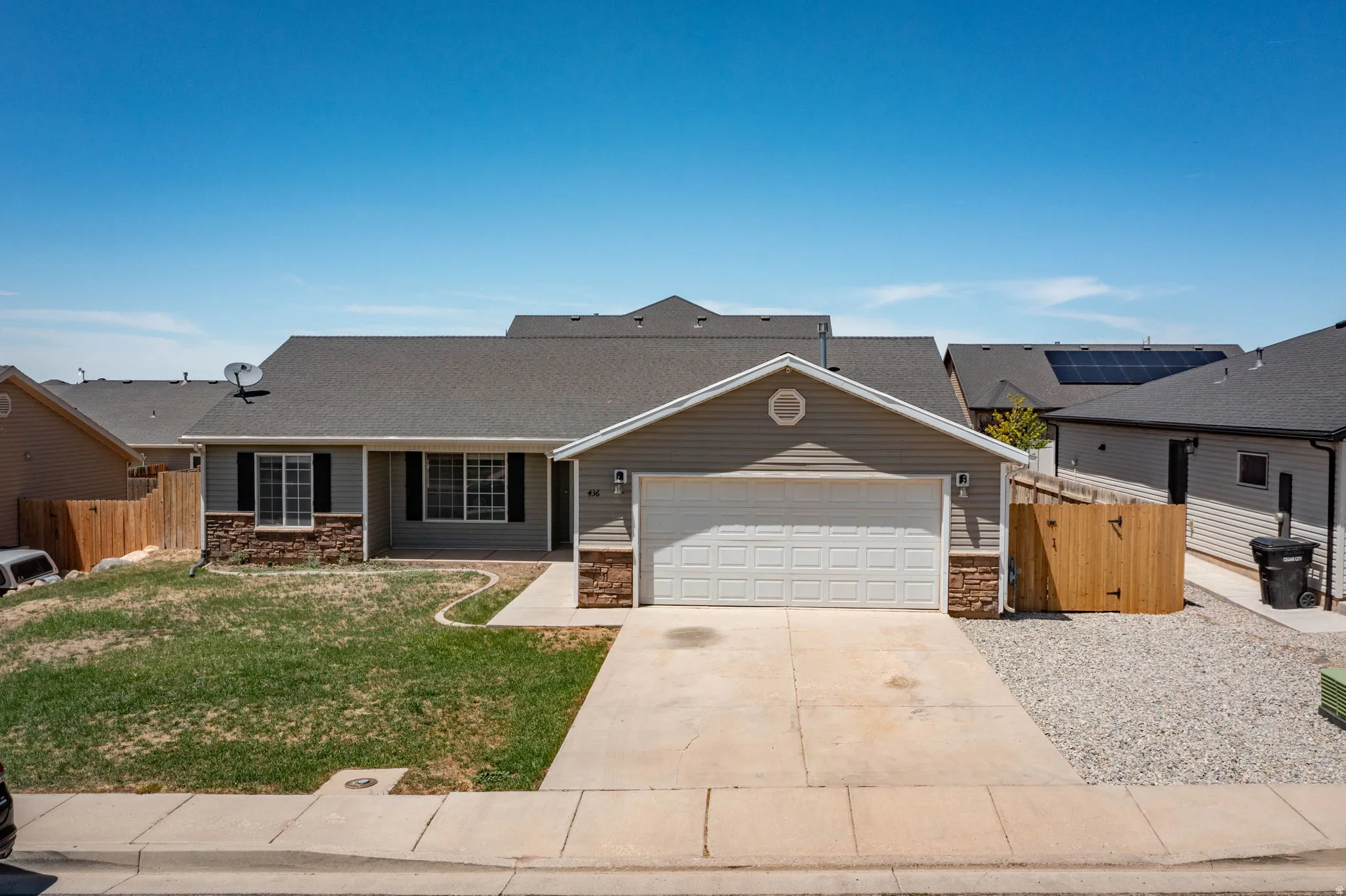 Single-story residence featuring light gray siding, stone accent facade, and a two-car garage with a concrete driveway