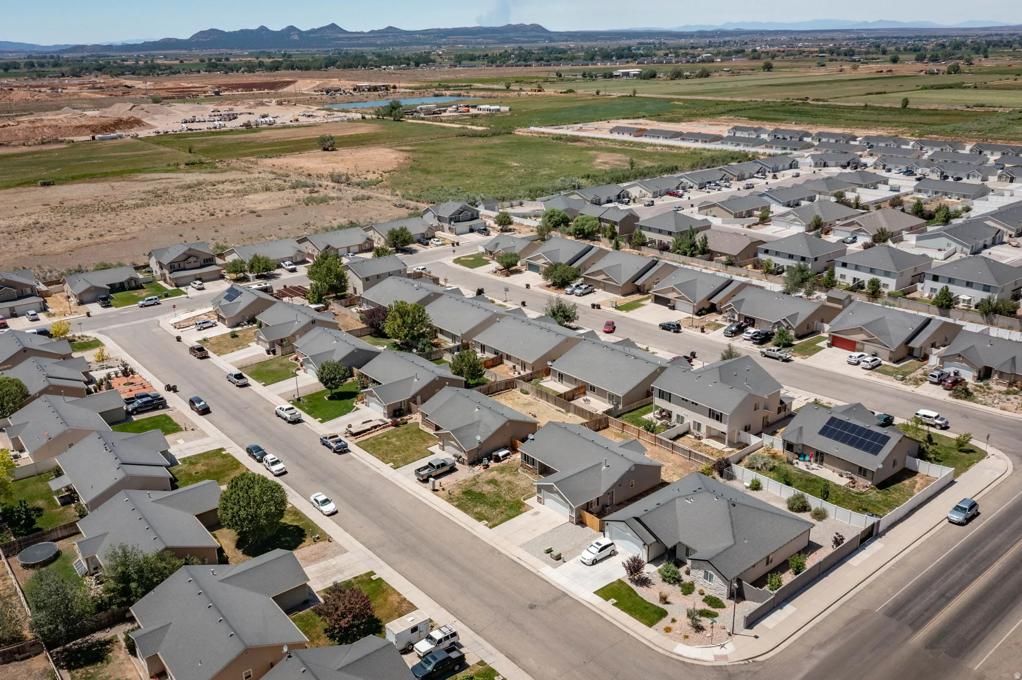 Aerial perspective showcasing a residential neighborhood with single-family homes, gray shingle roofing, and paved streets