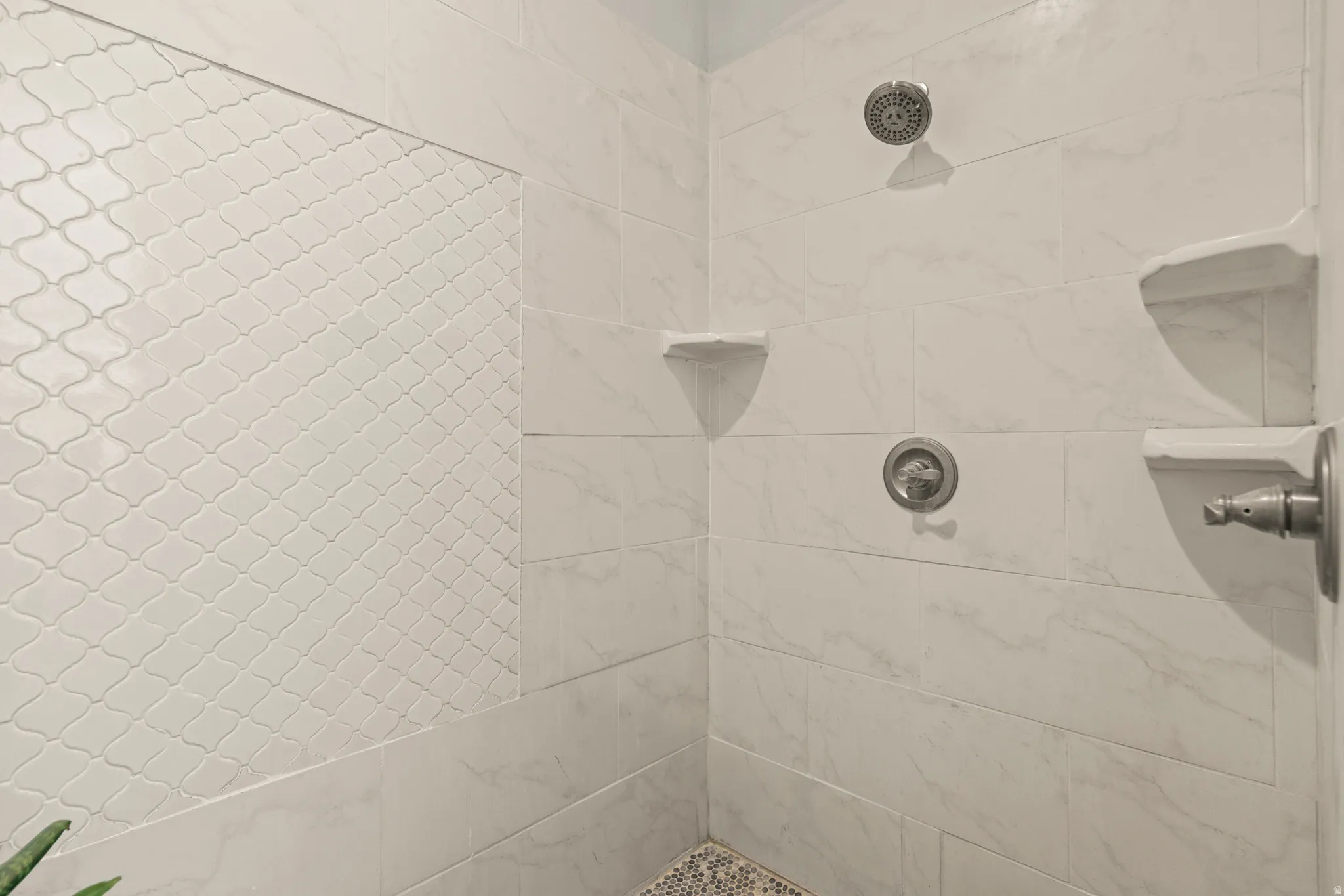 Tiled shower stall featuring a contrasting arabesque tile accent wall