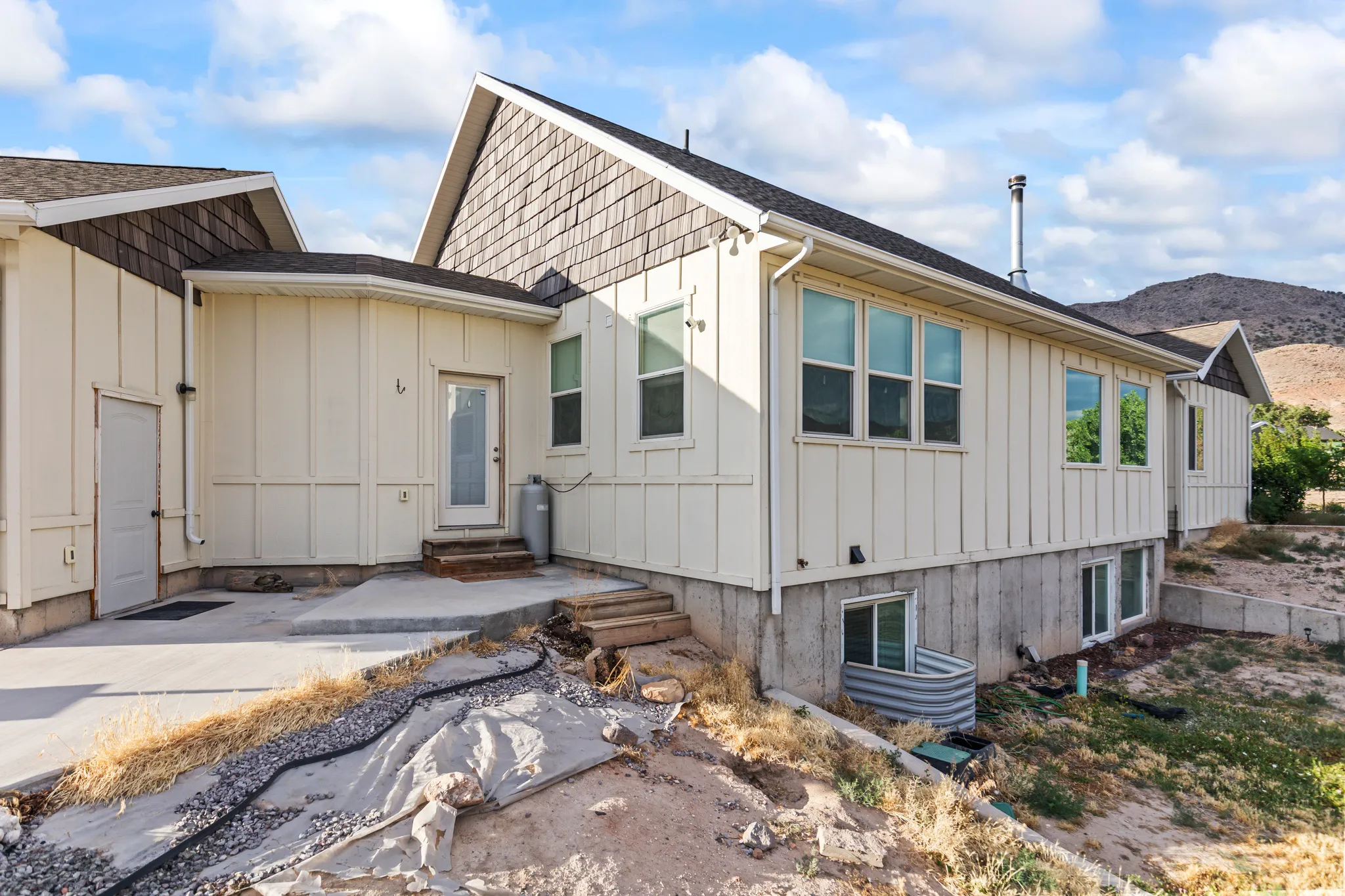 Exterior featuring board-and-batten siding, a partial stone foundation, and a shingle roof