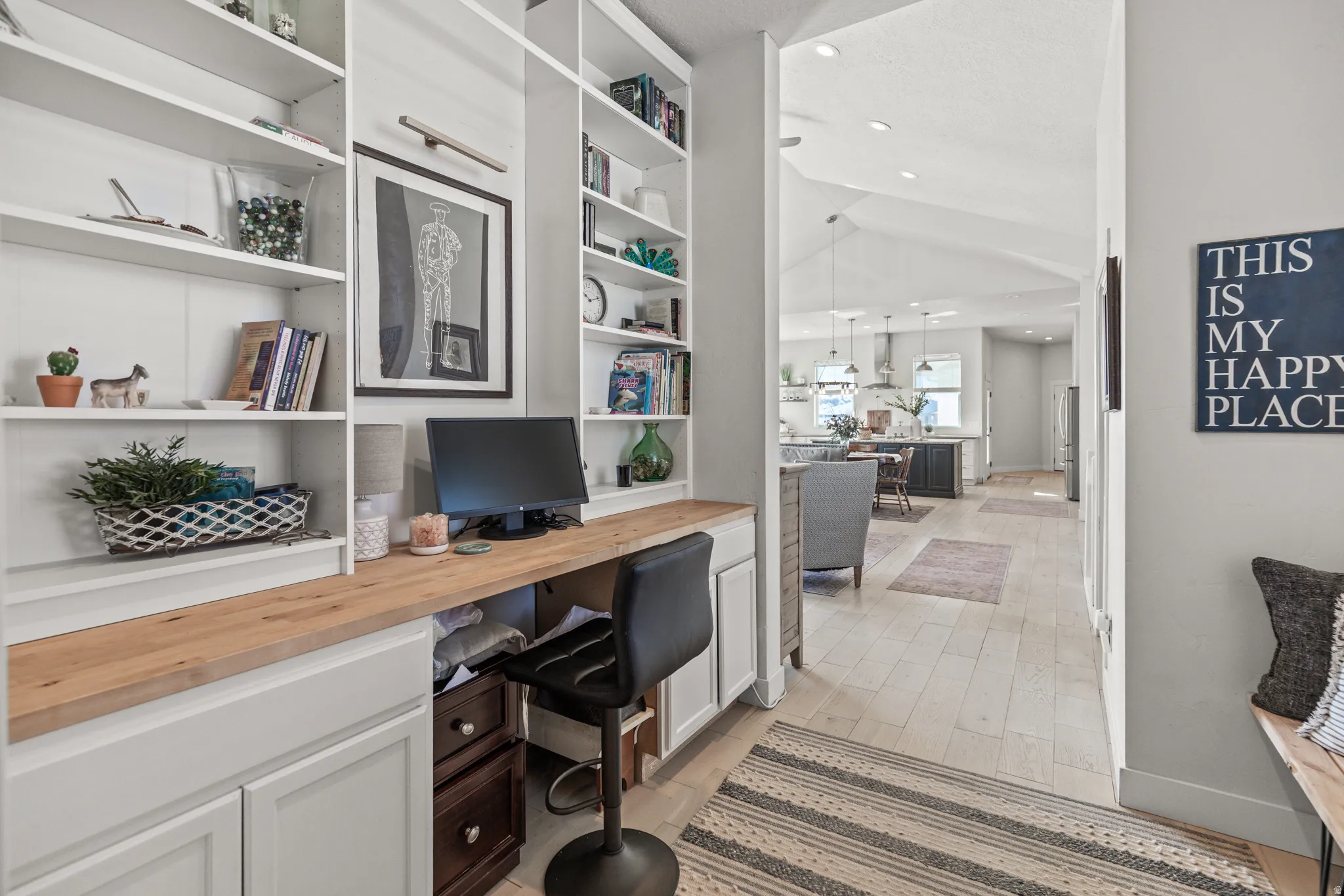 Integrated built-in desk with a wood-finish countertop, flanked by extensive white open shelving