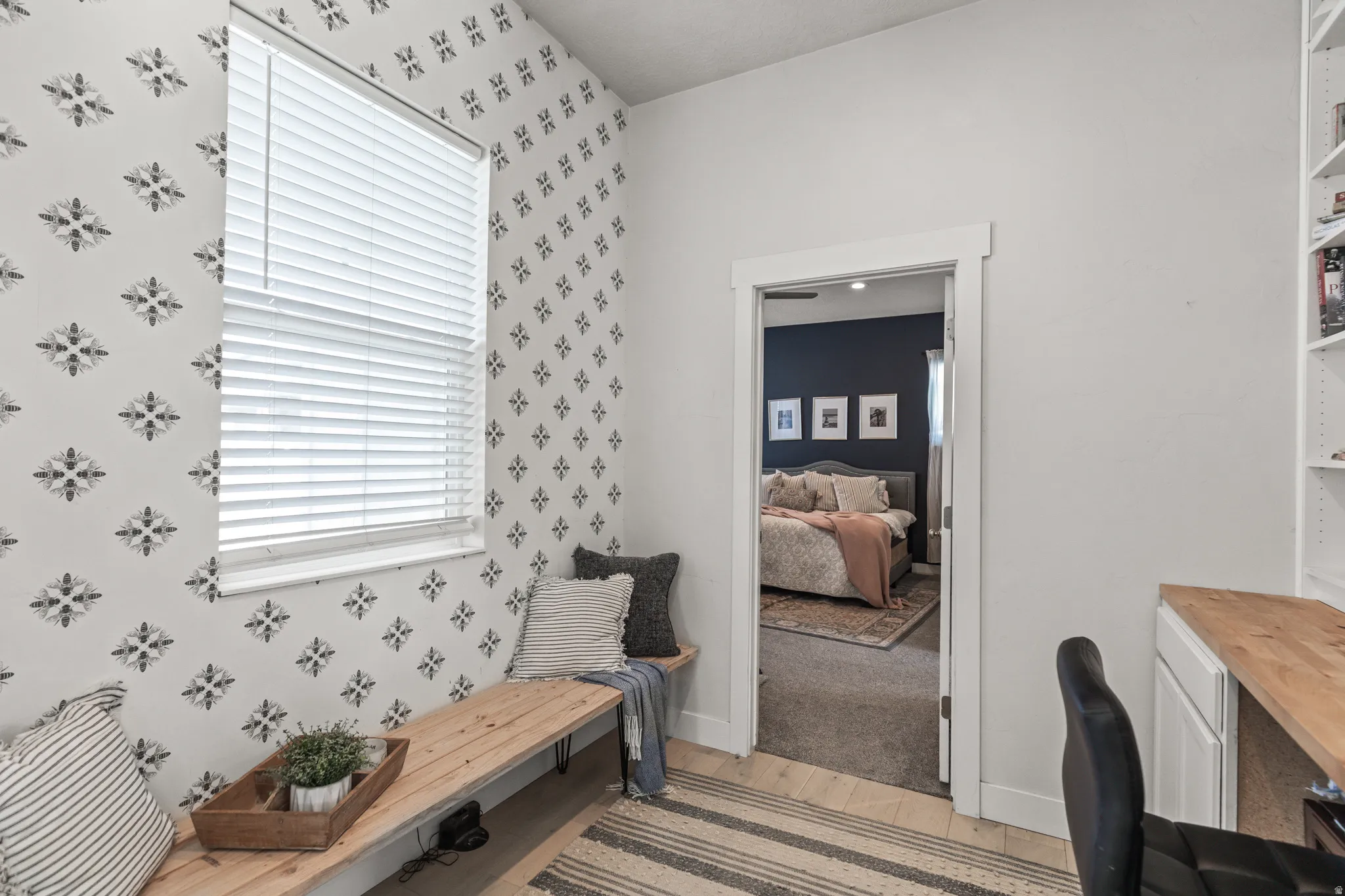 Room featuring a patterned accent wall, a built-in wooden bench, and a window with blinds