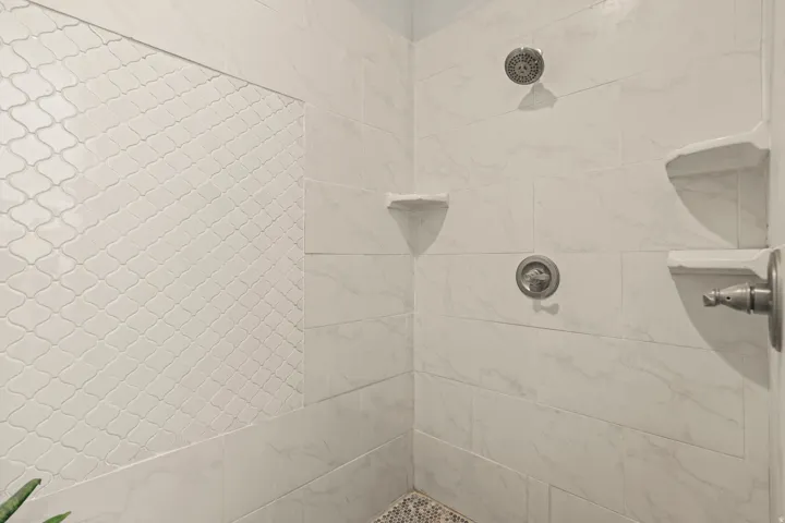 Tiled shower stall featuring a contrasting arabesque tile accent wall