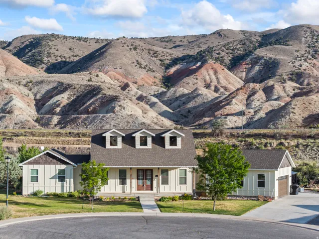 Mountain backdrop with a two-story residence featuring dormer windows and a covered front porch