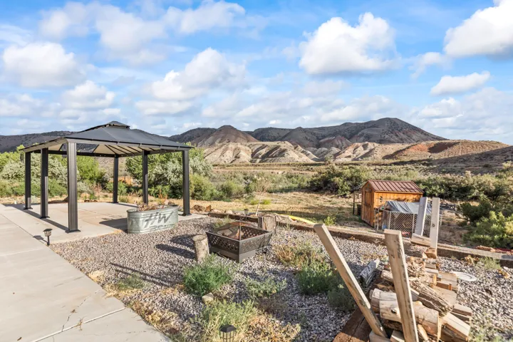 Outdoor living area featuring a permanent gazebo with a dark-colored roof, a concrete patio, and gravel landscaping
