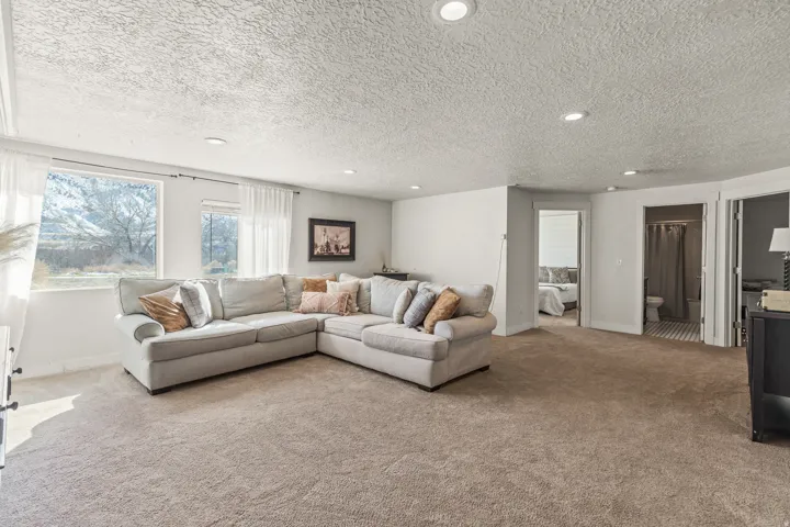 Spacious living area featuring neutral carpeting, recessed lighting, and bright natural light from multiple windows
