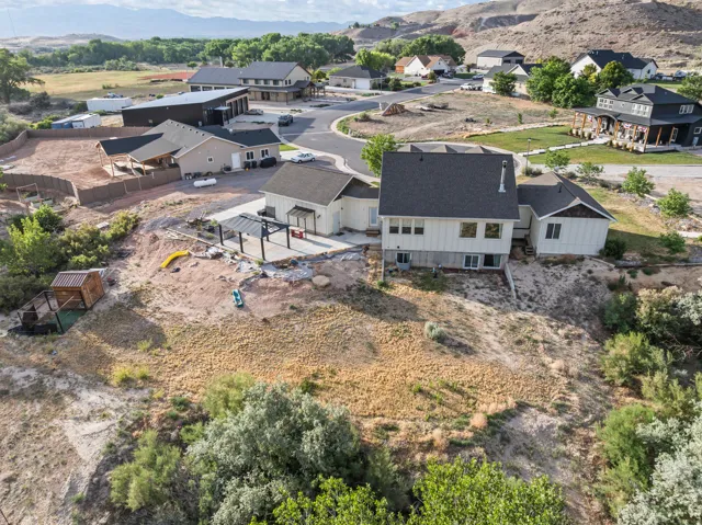Aerial perspective showcasing a residential property with a multi-level structure featuring a dark shingle roof and light-colored siding