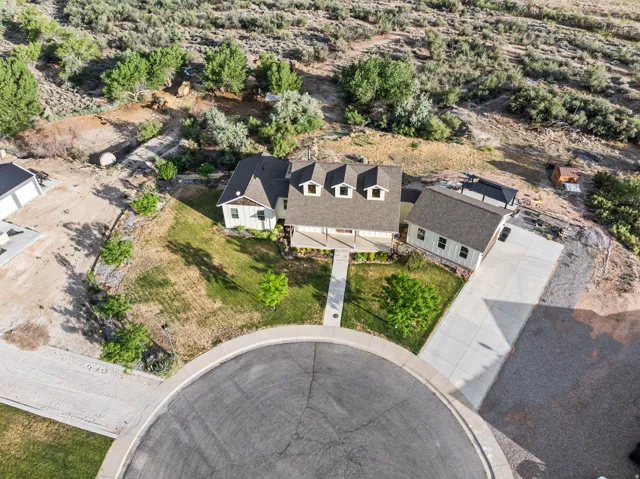 Property featuring a cul-de-sac location, paved driveway, mature landscaping, front porch, and detached garage