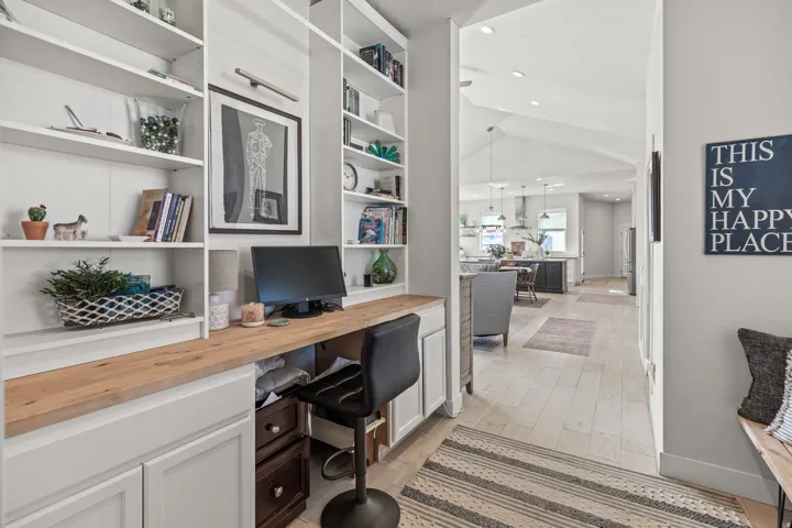 Integrated built-in desk with a wood-finish countertop, flanked by extensive white open shelving