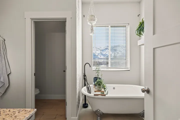 Freestanding clawfoot bathtub with a wall-mounted matte black tub filler