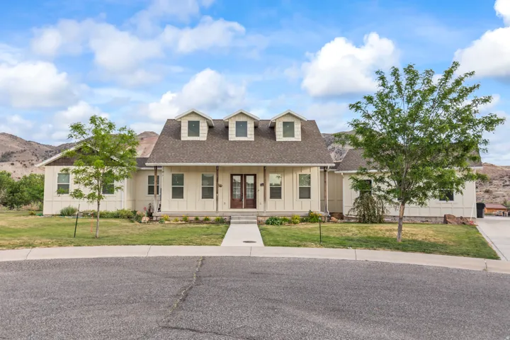 Single-story residence featuring a covered front porch with dark wood double entry doors, dormer windows, and a shingled roof