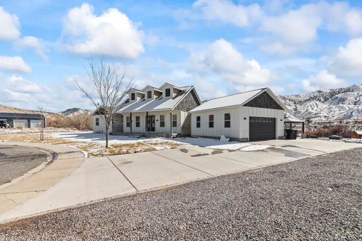 Modern farmhouse-style residence featuring a white board-and-batten exterior, dark trim accents, and multiple dormer windows