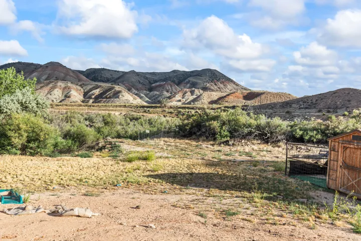 Expansive property with a wood storage shed, partially fenced area, and distant mountainous terrain