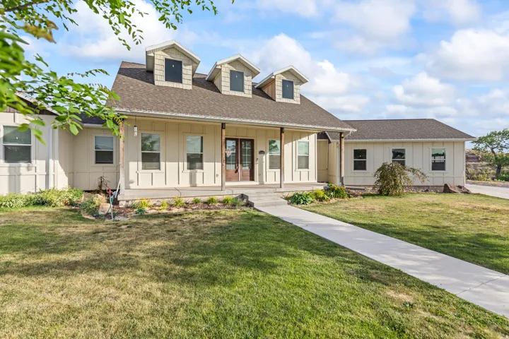 Ranch-style residence featuring a prominent covered porch entryway, board and batten siding, multiple dormer windows, and a dark shingle roof