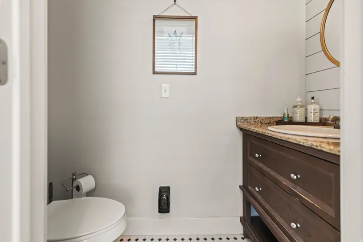 Bathroom featuring a dark wood-finish vanity with a granite countertop, undermount sink, and shiplap accent wall