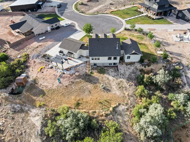 Spacious property featuring a large concrete patio with a modern pergola, an extensive sloped backyard, and mature surrounding foliage
