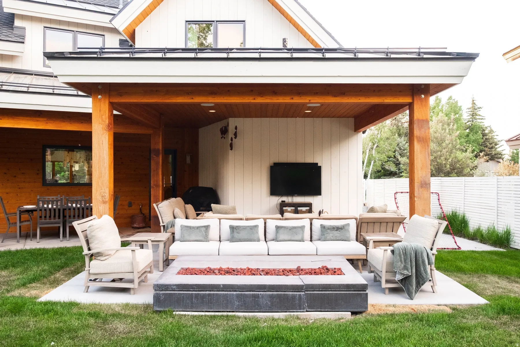 Expansive concrete patio featuring a covered outdoor seating area with wood-clad posts and ceiling